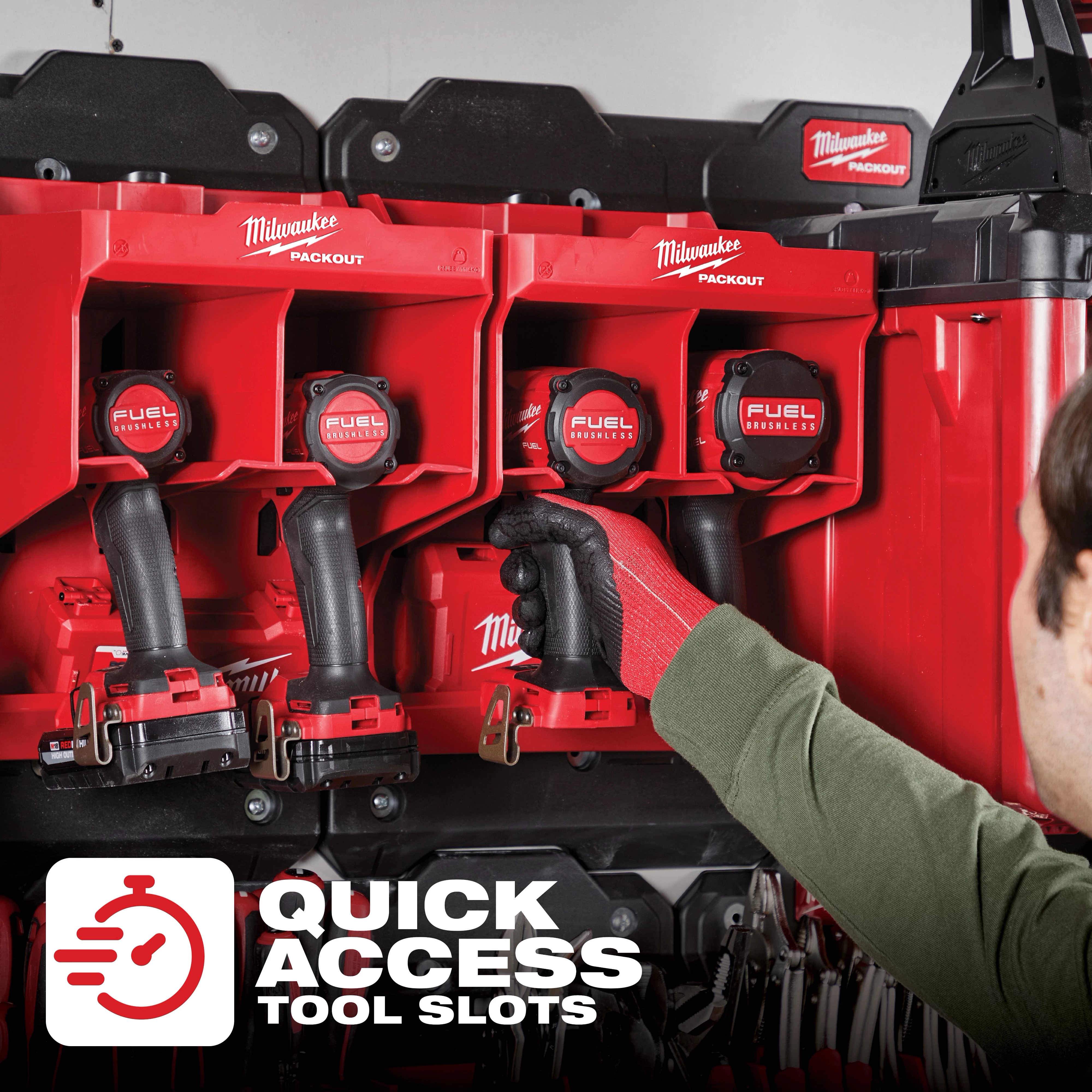 Person wearing a green shirt and red gloves placing a drill into the PACKOUT Tool Station's quick access tool slots with four drills.