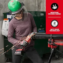 A person is using an angle grinder, wearing safety gear and the Women's FREEFLEX™ Hybrid Tee - Long Sleeve in purple. The shirt features moisture-wicking fabric and anti-odor technology as noted in the text on a red background on the right side of the image.