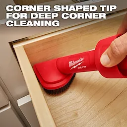 A person uses the red AIR-TIP™ Rotating Corner Brush Tool to clean the corner of a wooden drawer. The brush head is shaped to fit into corners. Text overlay reads "Corner Shaped Tip for Deep Corner Cleaning."
