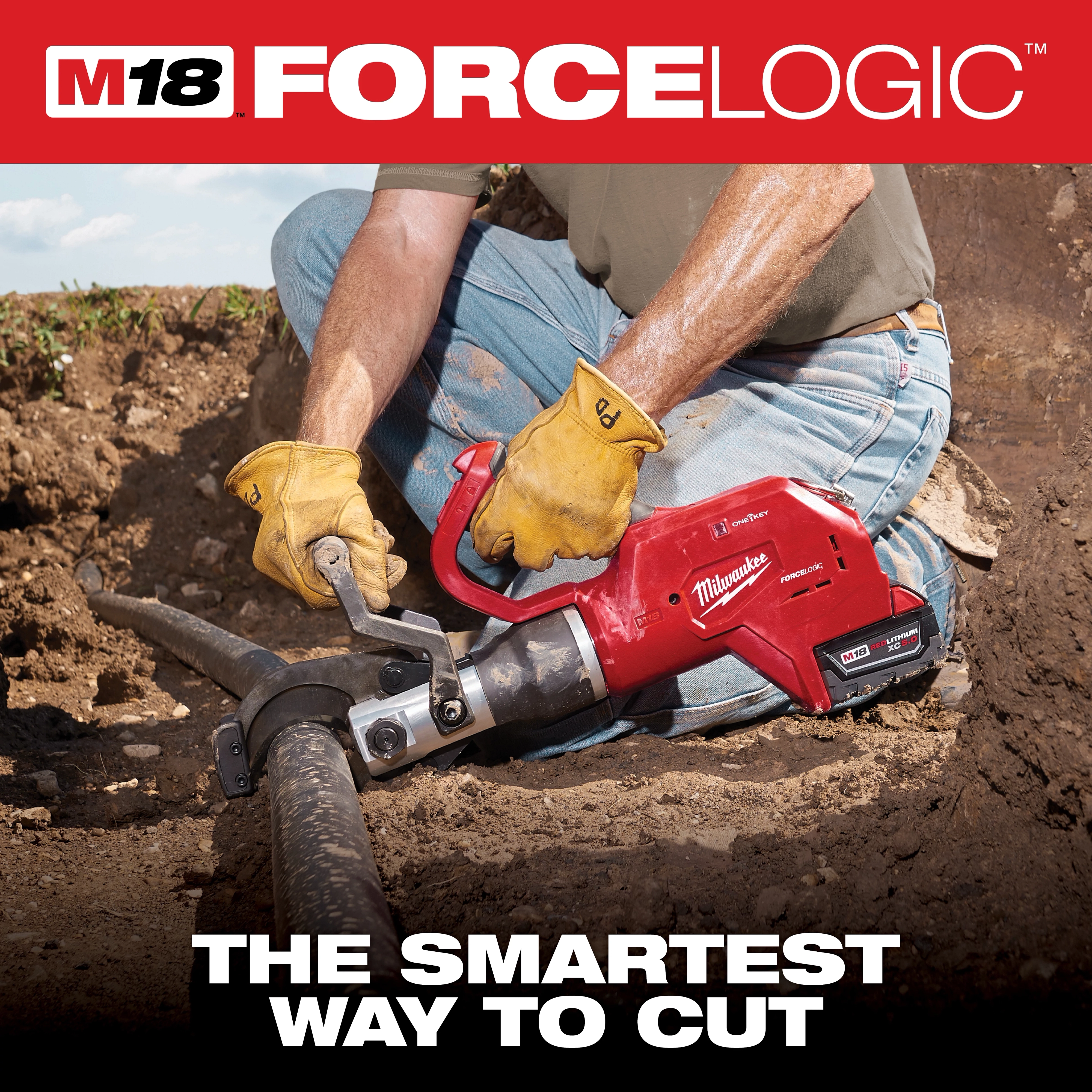 The M18 FORCE LOGIC Underground Cable Cutter is being used by a worker wearing gloves and jeans to cut a thick cable underground. The device is held with both hands, and the cutting process is taking place in a dirt trench.
