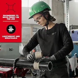 A worker wearing the Women's FREEFLEX™ Hybrid Tee - Long Sleeve, gloves, and a green helmet, operates in an industrial setting. Red text on the left highlights features: "Engineered to move freely on the job" and "Lightweight and breathable." The tee has a Milwaukee Tool logo.