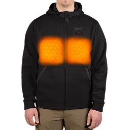 Front view of a person wearing a black M12™ Heated Hoodie. The hoodie features two glowing orange heating zones on the chest, indicating its heating elements. The hoodie has a full zipper, two front pockets, and a small red control button on the upper chest.
