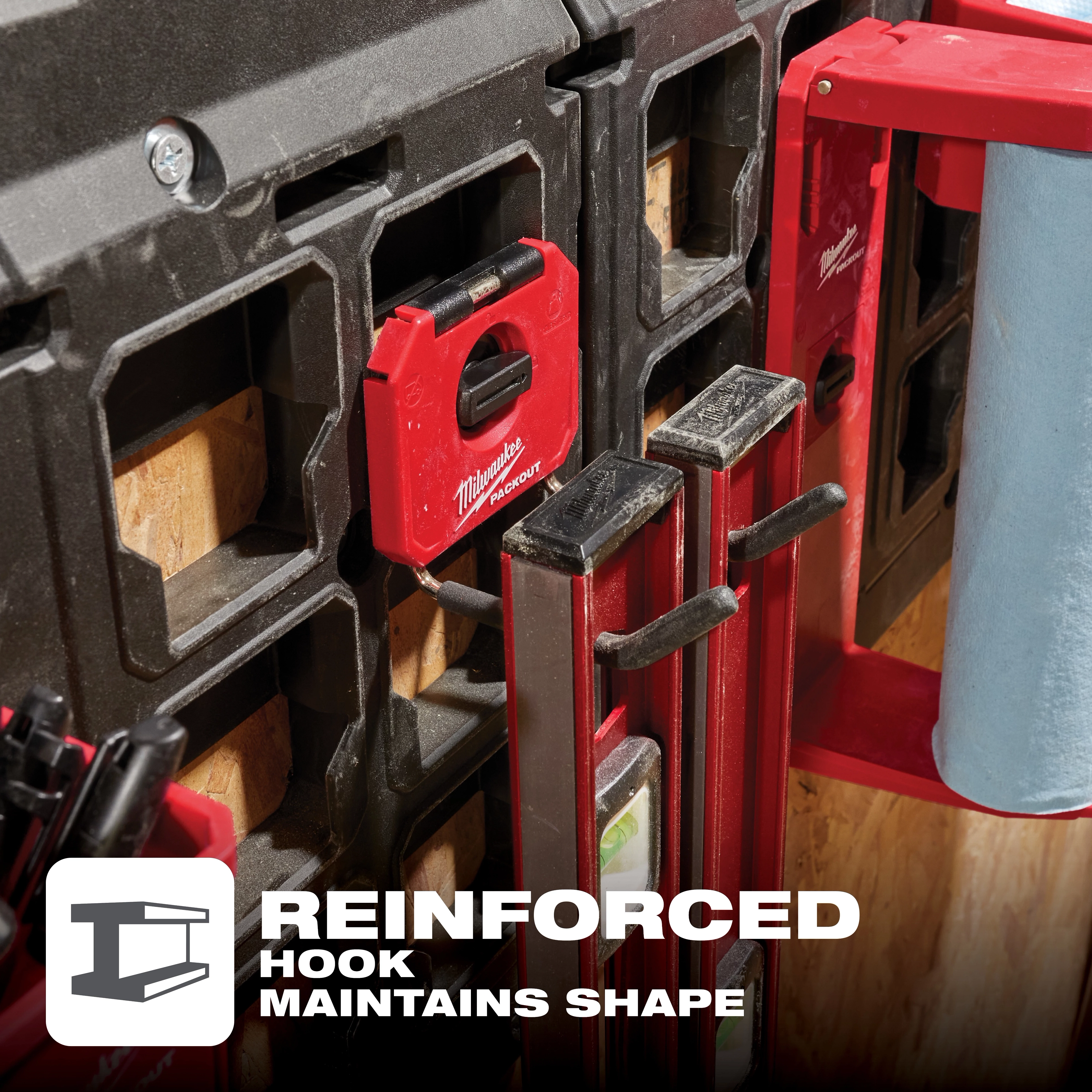 Milwaukee PACKOUT 4" Straight Hook attached to a storage system, holding measuring tools with a nearby paper towel holder. Text reads "Reinforced Hook Maintains Shape."