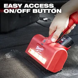 A person’s hand is holding a red M12™ AIR-TIP™ Utility Nozzle, which is being used on a carpeted surface. The text "EASY ACCESS ON/OFF BUTTON" is displayed at the top of the image. The nozzle has built-in LED lights and a prominent on/off button.