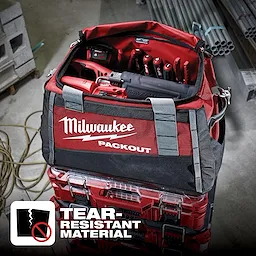 Milwaukee Packout tool bag filled with tools on top of Packout storage boxes. Tear-Resistant Material text and icon are visible.