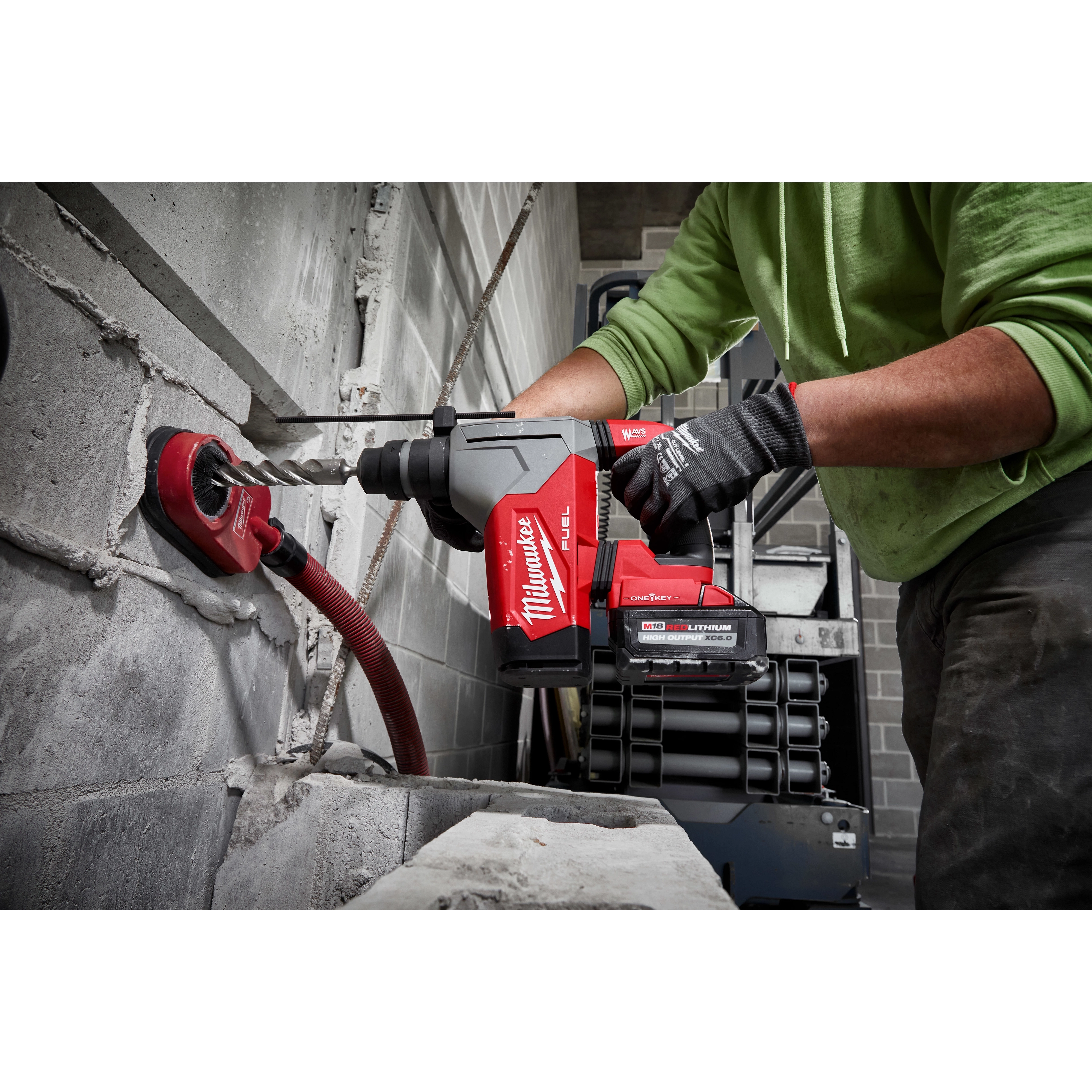 Person using a red M18 FUEL 1-1/8" SDS Plus Rotary Hammer to drill into a grey concrete block wall.