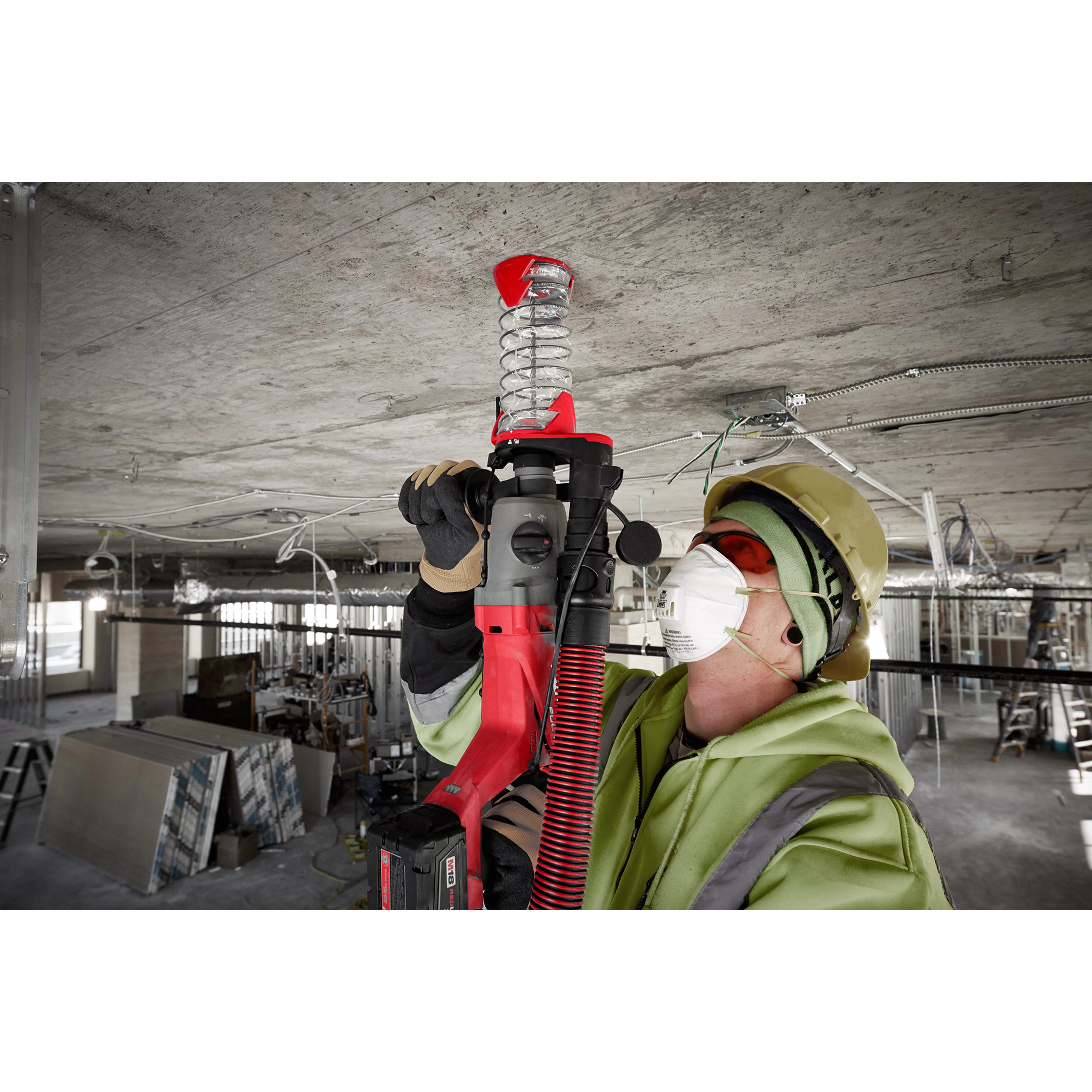 Worker using an SDS Plus DUST TRAP Drilling Shroud Bulk 10 on a red drill to minimize dust while drilling into a concrete ceiling.