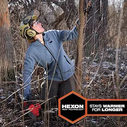 A person wearing protective gear works in a forest while wearing the M12™ Heated Hoodie. The hoodie is gray with black zippers and trim, featuring Hexon heat technology. A hexagonal badge on the image reads “Hexon Heat Technology™ stays warmer for longer.”