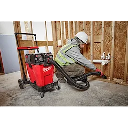 Person using the M18 12 Gallon Dual-Battery Wet/Dry Vacuum Kit to clean a construction site.