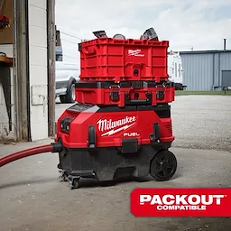 The image shows the M18 FUEL™ 9 Gallon Dual Battery Dust Extractor with PACKOUT™ Compatibility and VACLINK™. The red and black dust extractor has wheels, a hose, and stacked PACKOUT™ storage units on top, and is branded with "Milwaukee FUEL." A "PACKOUT Compatible" label is visible.