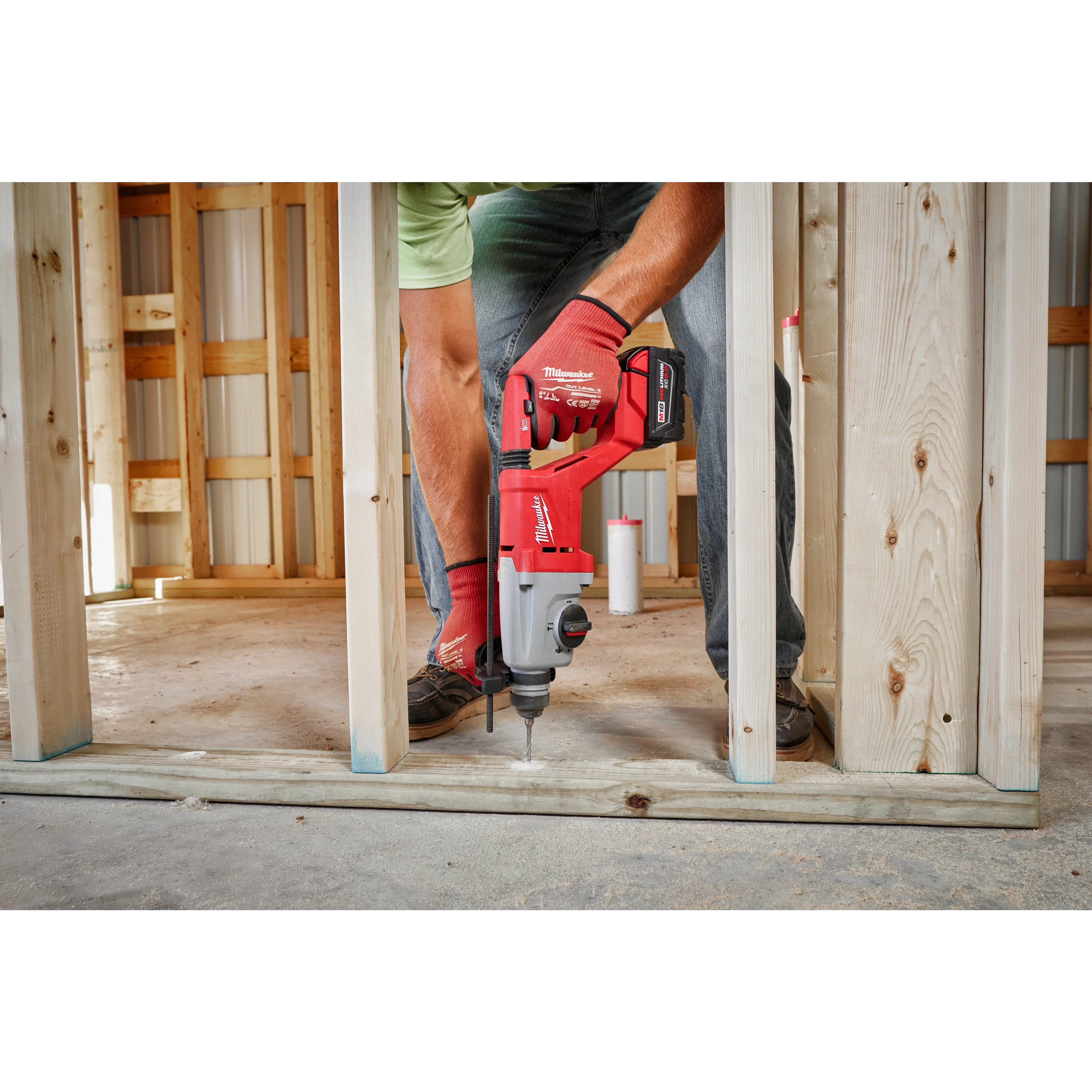 Man using the M18 Brushless 1” SDS Plus D-Handle Rotary Hammer to drill into the base of a wooden structure under construction.
