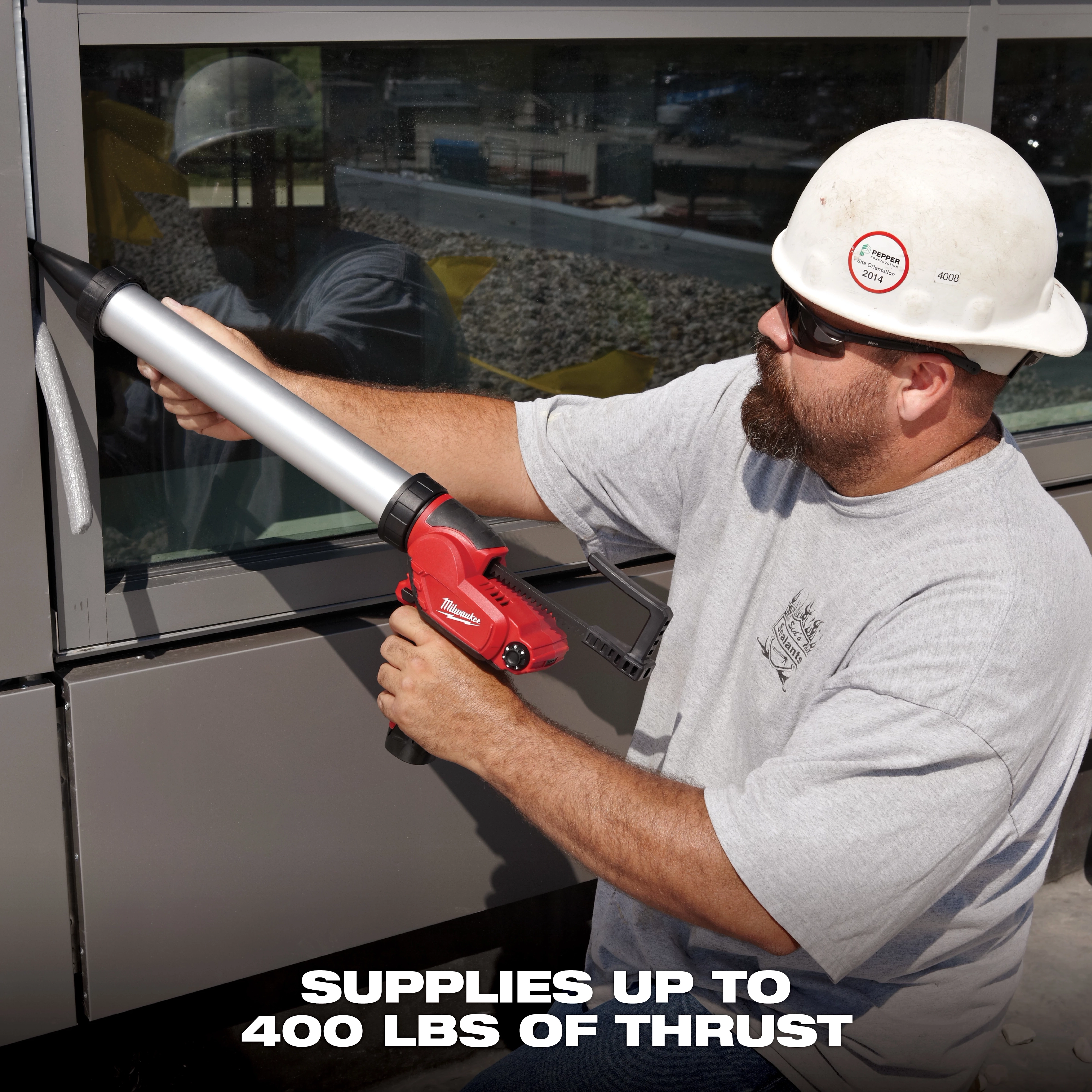 A person operates an M12 12-Volt Lithium-ion Cordless 20 oz. Aluminum Barrel Caulk and Adhesive Gun Kit on a window frame. The image text states that the device supplies up to 400 lbs of thrust.