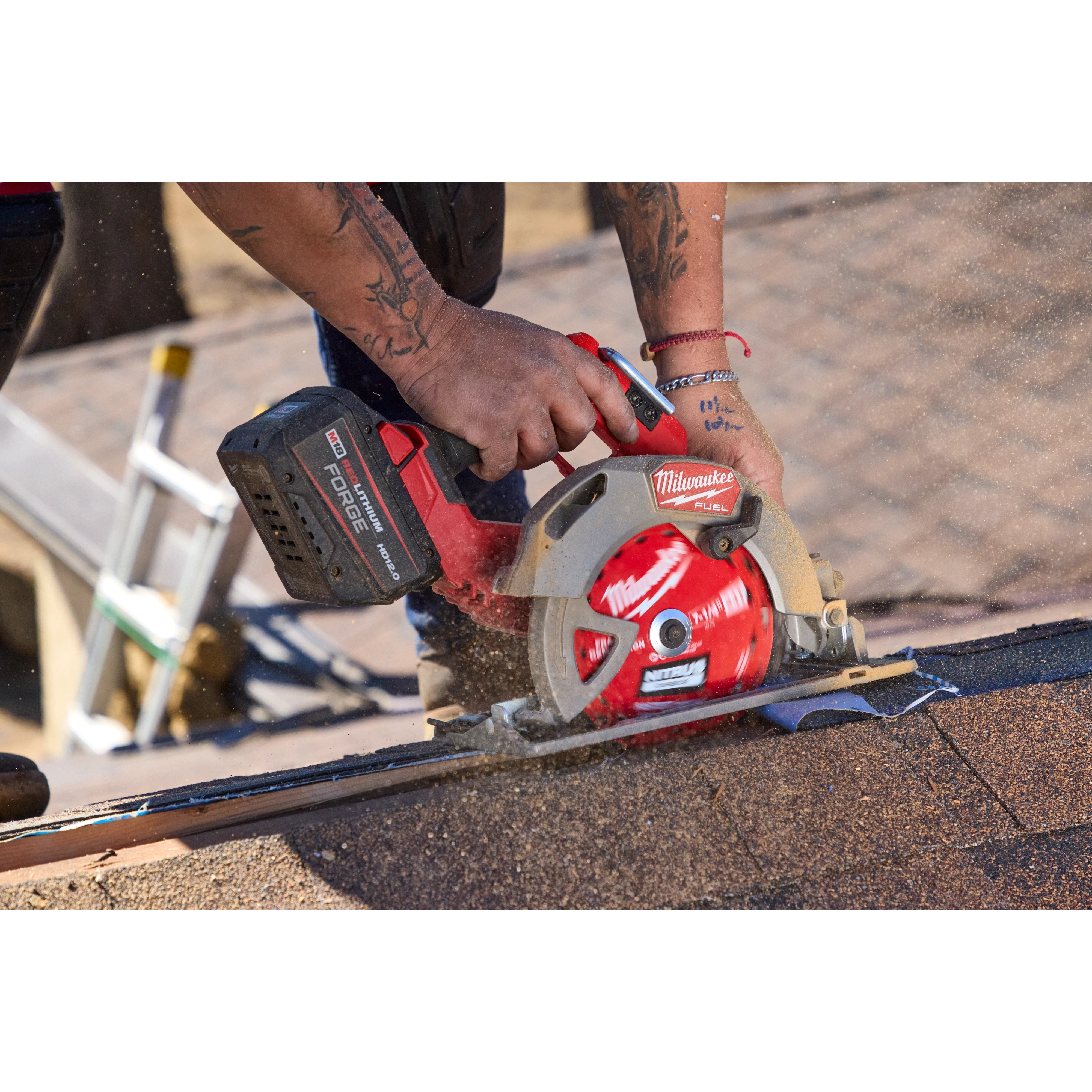 A person is using a Milwaukee circular saw equipped with a 7-1/4” 24T NITRUS™ Carbide Framing & Demolition Circular Saw Blade to cut through roofing material. The saw is generating dust, indicating active cutting. The user is wearing a red bracelet and has tattoos on their forearm.