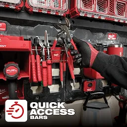 Person organizing tools on a wall-mounted PACKOUT Tool Rack with several red-handled tools securely placed in the rack slots.