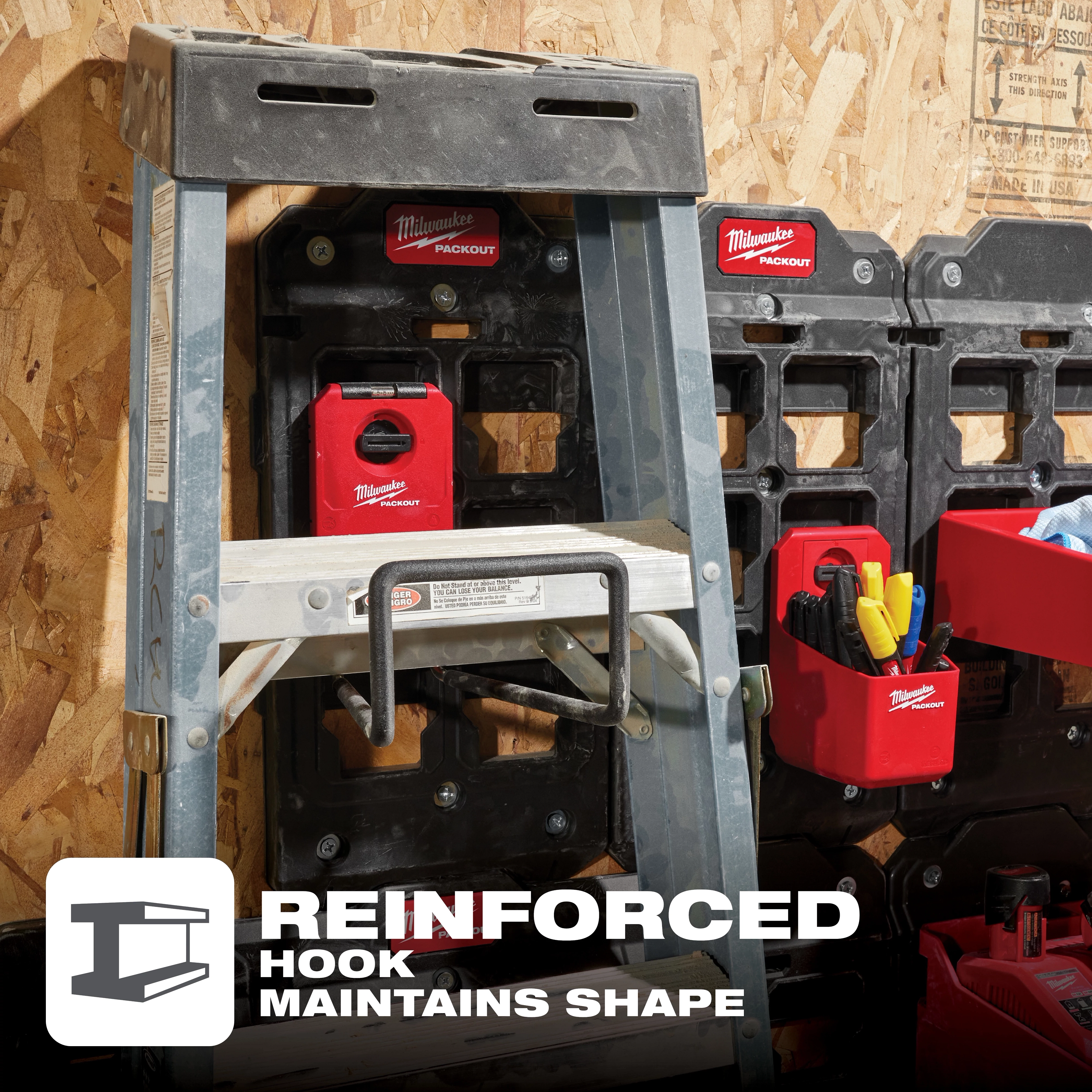 The image features a PACKOUT Wide Hook holding a ladder on a workshop wall with multiple PACKOUT storage units nearby, showing reinforced hook support.