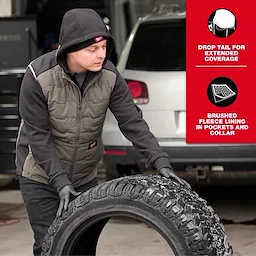 A person wearing the FREEFLEX™ Lightweight Insulated Vest in an outdoor setting rolls a large tire. The vest features drop tail for extended coverage and brushed fleece lining in pockets and collar.