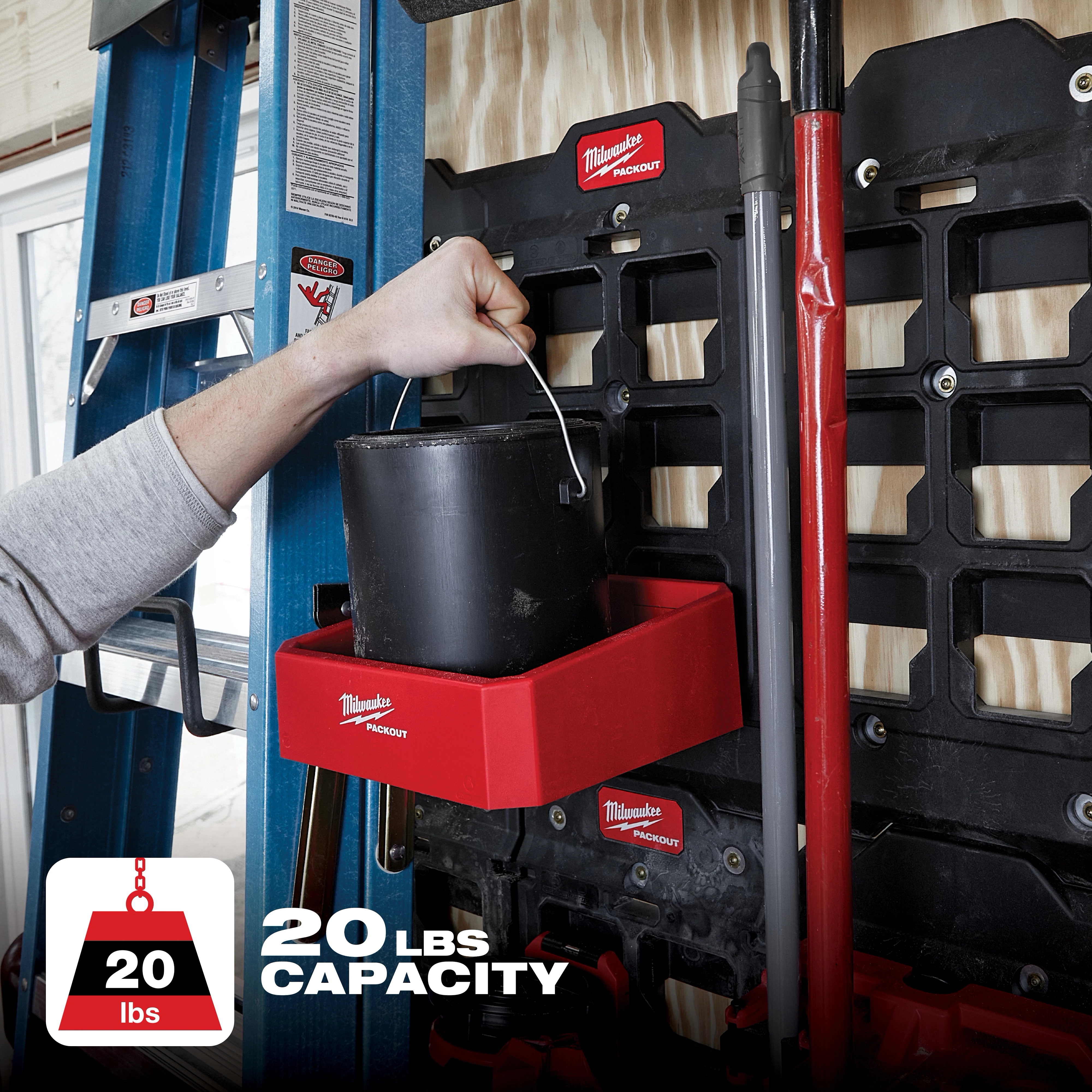 The PACKOUT Compact Shelf is red, mounted on a storage rack, and holds a black container. It has a 20 lbs capacity.