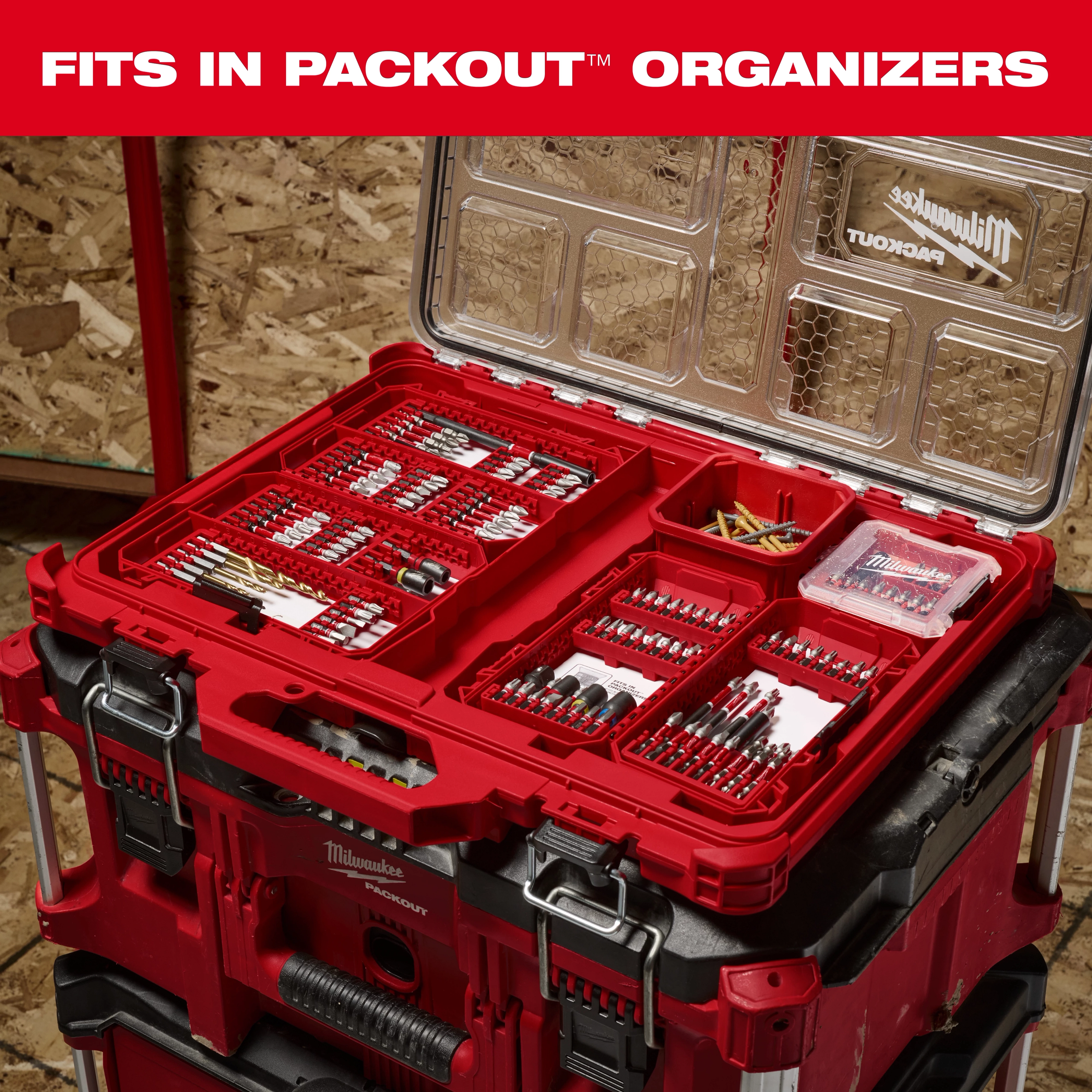 The image shows a Milwaukee PACKOUT organizer box opened to reveal various SHOCKWAVE™ fits in PACKOUT™ drill and driver bits neatly arranged inside. The container sits on top of other PACKOUT units, demonstrating its compatibility and storage capacity.