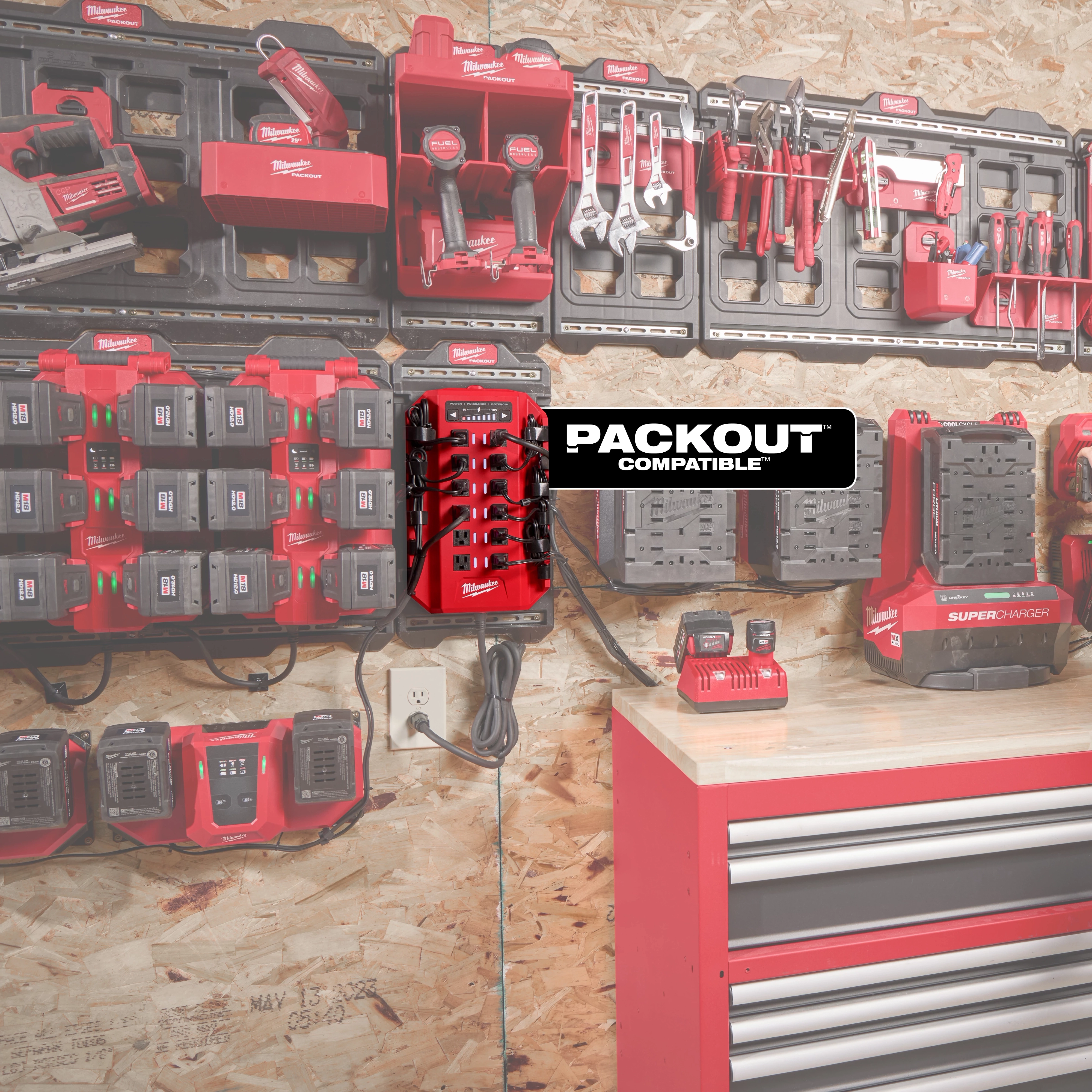 A Power Manager – 15 Amp Circuit, 20 Amp Circuit is mounted on a workshop wall, surrounded by various power tools, chargers, and tool storage solutions. The image shows the organized setup and highlights the device's compatibility with PACKOUT storage systems.