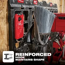 The PACKOUT 9” Straight Hook is attached to a wall-mounted grid, holding cleaning tools like a broom and dustpan. Text reads: "Reinforced Hook Maintains Shape."