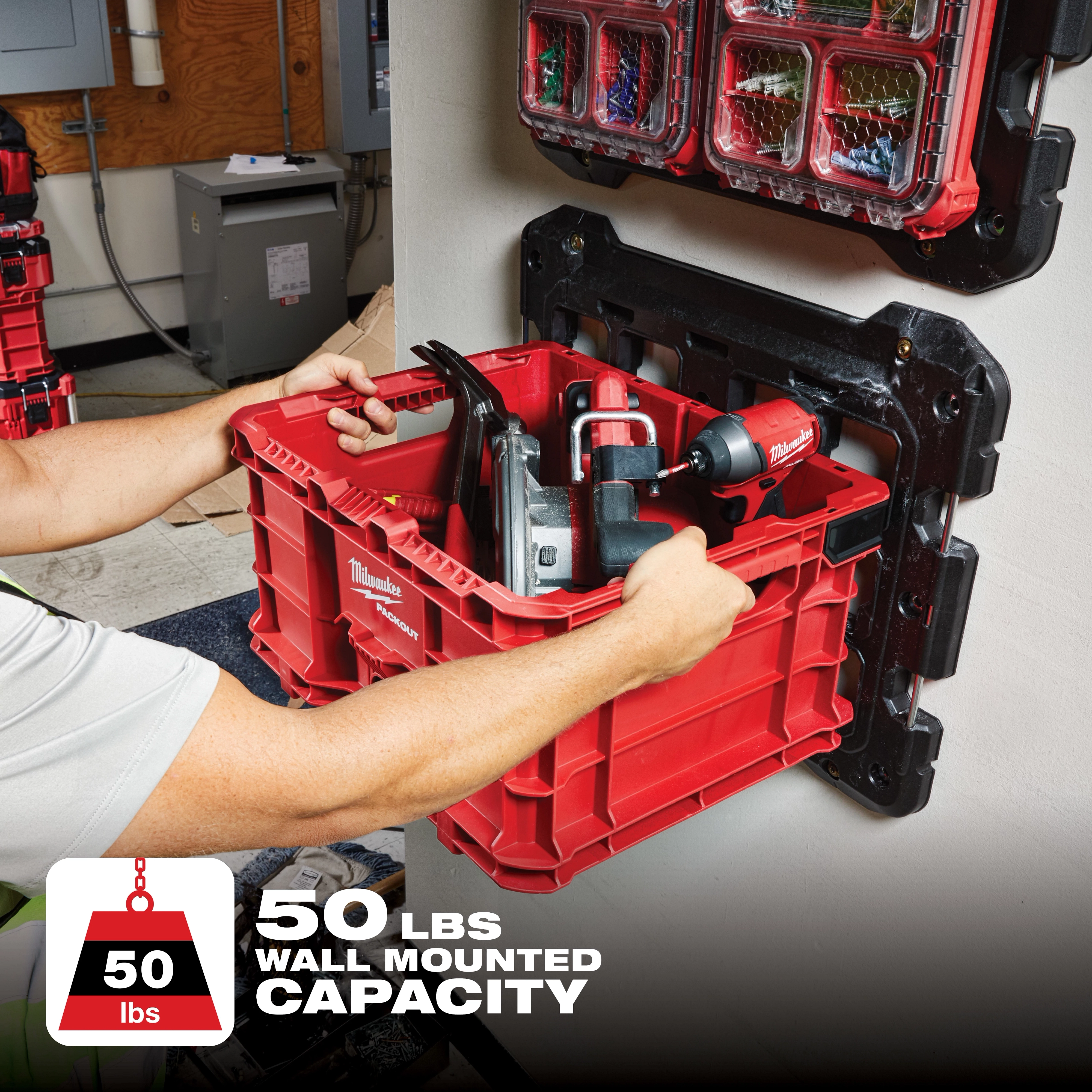 Person mounting a red PACKOUT Mounting Plate holding tools, rated for a 50 lbs wall-mounted capacity, onto a wall.