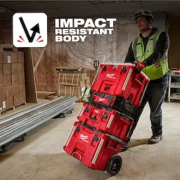 Person in a workshop pulling stacked red PACKOUT 40QT XL Cooler and toolboxes on a cart. Text reads "Impact Resistant Body".