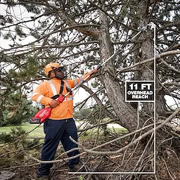 A person in an orange safety outfit and helmet uses the M18 FUEL™ Pole Saw w/ QUIK-LOK™ Kit to trim branches from a large tree. The image highlights the 11-foot overhead reach of the pole saw.